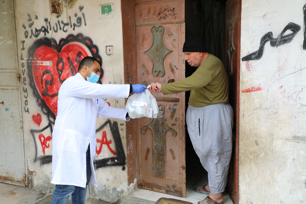 Un trabajador de UNRWA le entrega de medicamentos a un anciano palestino en la Franja de Gaza.