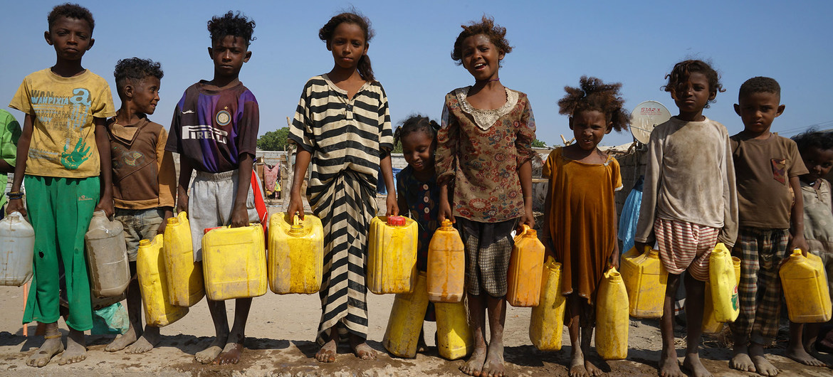 Niños yemeníes desplazados en un asentamiento de Adén sostienen contenedores durante la distribución de agua, que se hace dos veces al día.