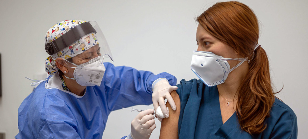 Una sanitaria pone la primera dosis de la vacuna contra el COVID-19 a una paciente en Colombia. 