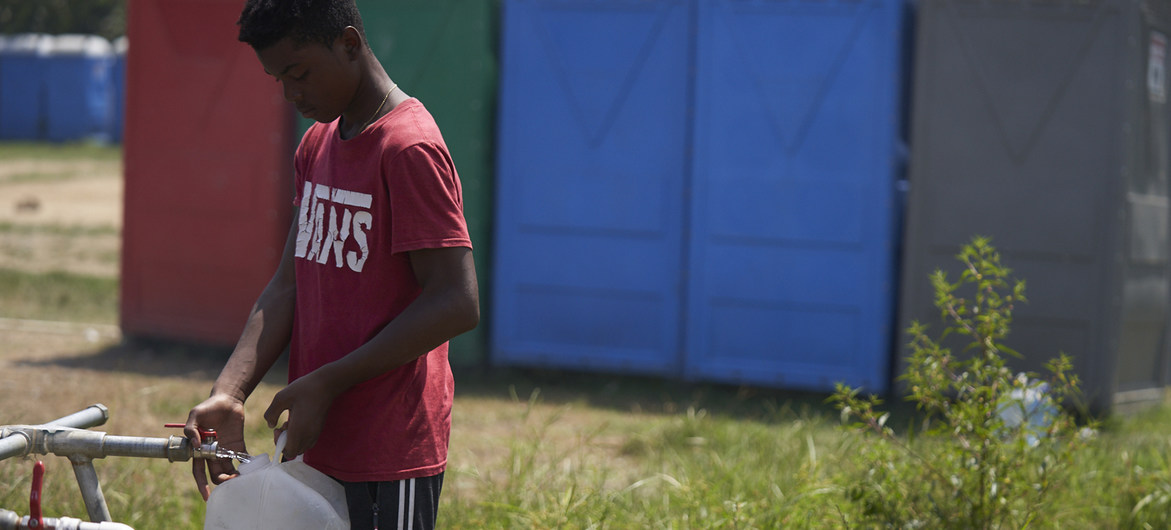 Un adolescente colecta agua potable en una estación migratoria del Darién, en Panamá.