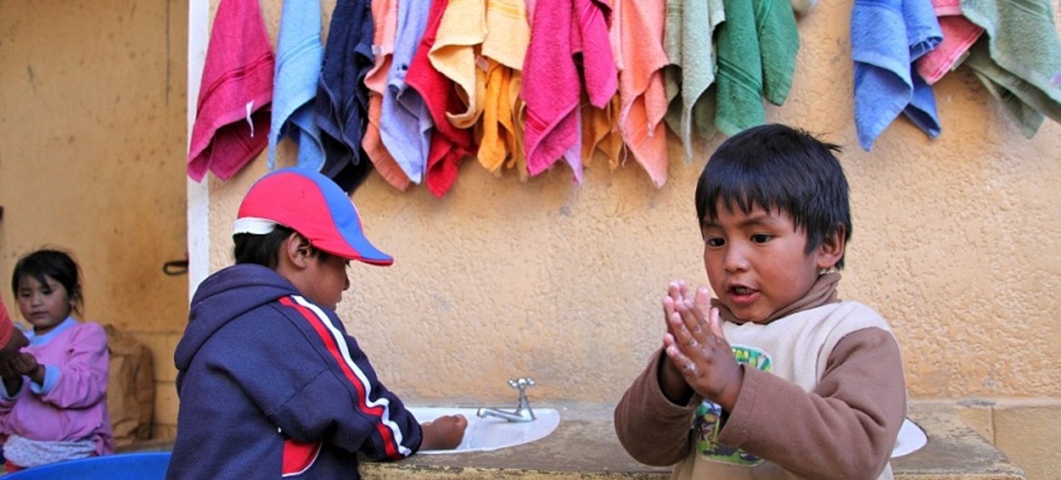 Dos niños en Bolivia se lavan las manos en una estación apoyada por UNICEF.