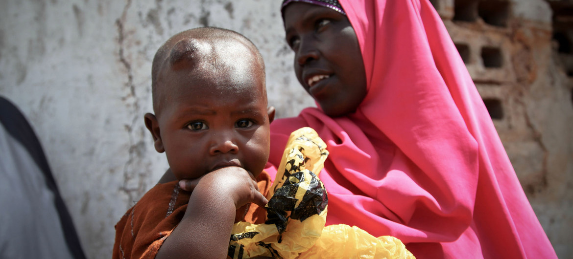 Una mujer y su hijo pequeño esperan fuera de una clínica médica gratuita en Kismayo, Somalia.