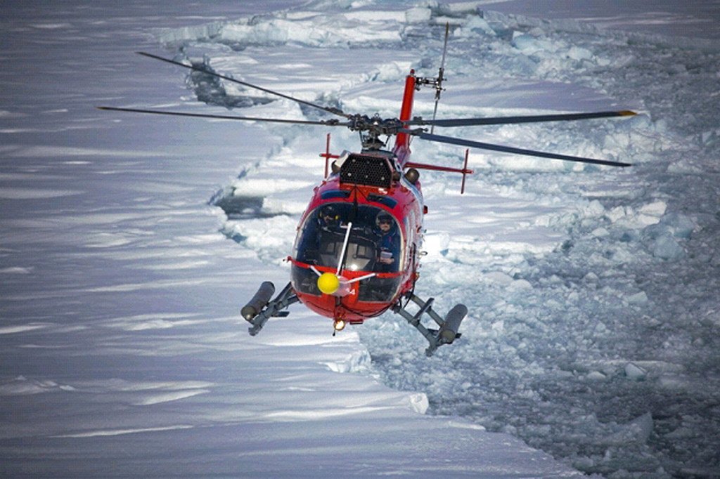 Un helicóptero sobrevuela el Ártico, donde se los nuevos récords de temperaturas y el deshielo de los glaciares ya ha dejado una huella palpable del efecto que tienen estas en nuestro planeta.