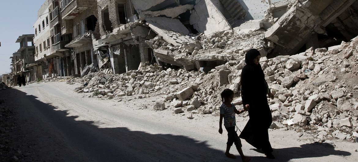 Una niña y una mujer caminan frente a edificios destruidos en la ciudad de Maarat al-Numaan, en Idlib, Siria.