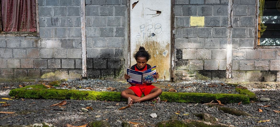 Una niña lee un libro en la entrada de su casa en Papua, una de las provincias más pobres de Indonesia.