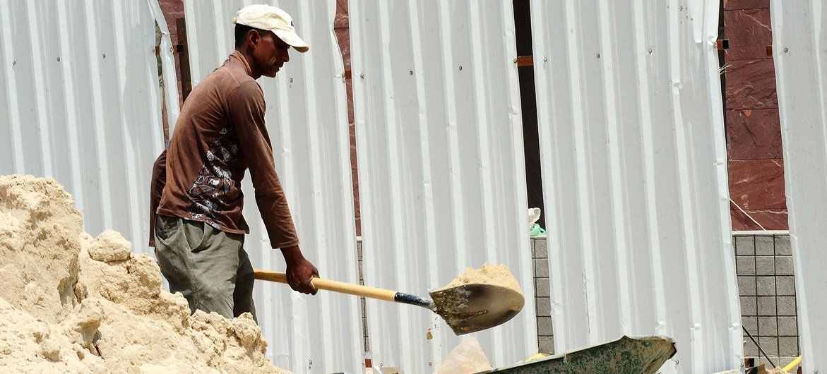 Un trabajador de la construcción palea arena.