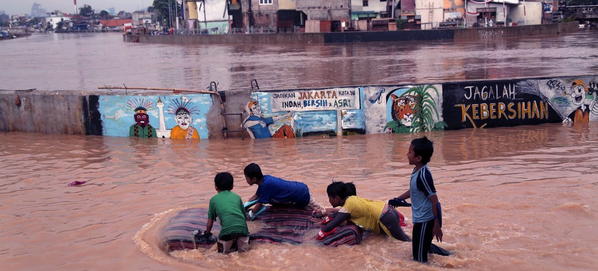 Unos niños juegan en las aguas desbordadas del río Ciliwung, en Yakarta Oriental, Indonesia.