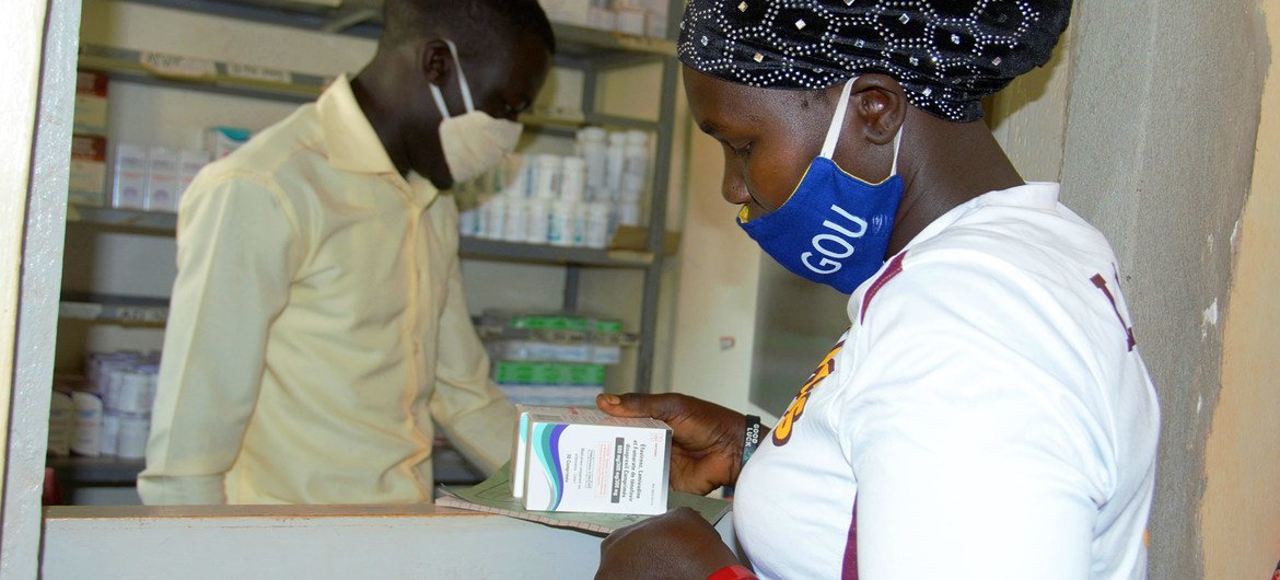 Una mujer que vive con VIH recibe su medicación en un centro de salud de Uganda durante la pandemia de COVID-19.