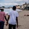 Dos menores de Gambia que cruzaron el Mediterráneo sin sus padres caminan en una playa de Italia.