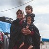 Una mujer viuda carga a su nieto en un campamento de desplazados en la provincia siria de Idlib.