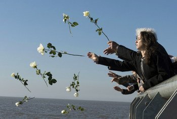 Visitantes lanzan flores blancas al río de la plata como símbolo de respeto en el Parque de la Memoria, Buenos Aires, Argentina.