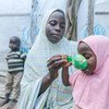 Una madre alimentando a sus hijos con cereales que ha recibido en un punto de distribución del Programa Mundial de Alimentos en Maiduguri, Nigeria