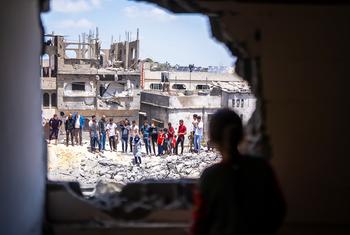 La gente observa los daños a las viviendas de un barrio en Gaza.