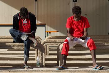 Adolescentes migrantes no acompañados leen panfletos informativos en Lampedusa (Italia) tras cruzar el Mediterráneo Central.
