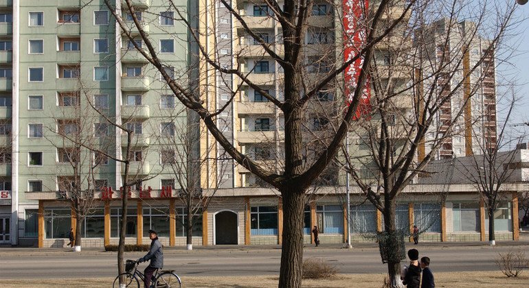Niños y adultos pasan por un edificio de apartamentos de gran altura en Pyongyang, Corea del Norte.